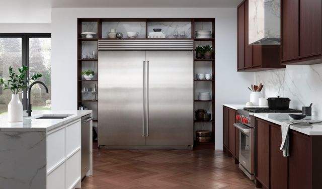 front view of a modern kitchen with a large sub-zero refrigerator built into the wall in the center, with built in shelving around it